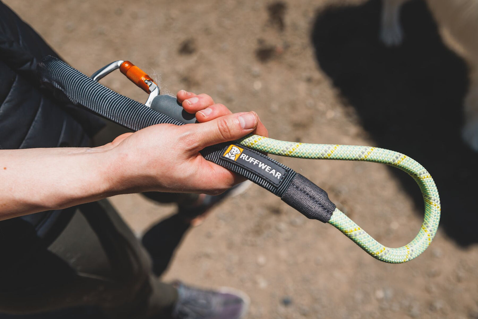 Close-up of a hand holding the Ruffwear Knot-a-Long leash in Moss Green showing the padded handle, Ruffwear branding, kernmantle rope loop, and lockable Crux Clip