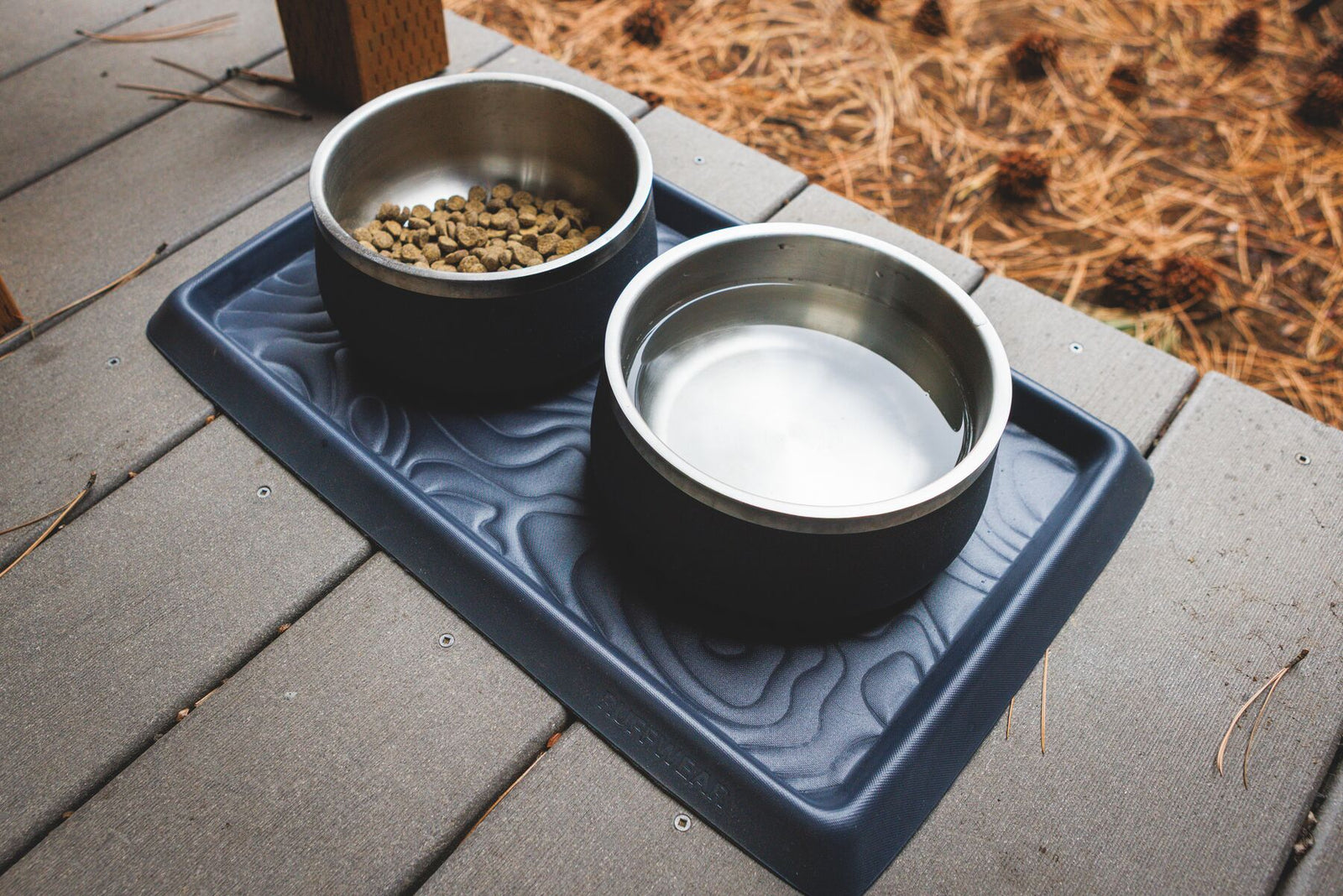 Ruffwear Basecamp Mat with two bowls on a wooden deck outdoors