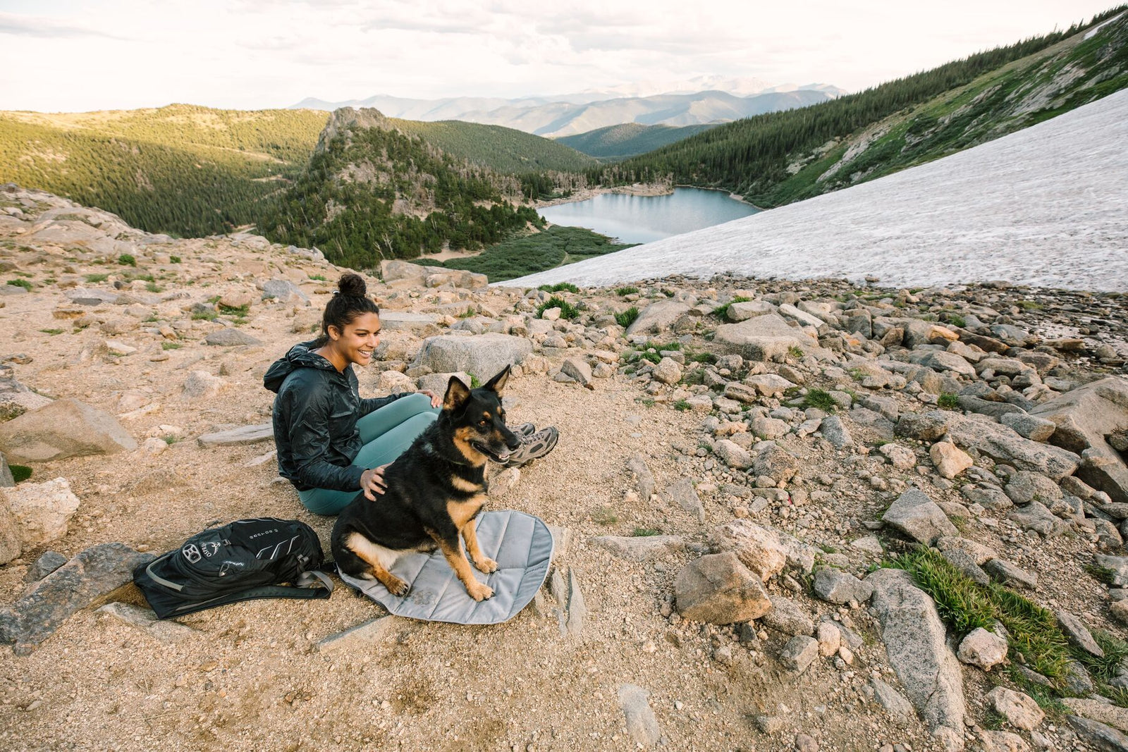 Dog sitting on Ruffwear Highlands Pad on rocky terrain in the mountains